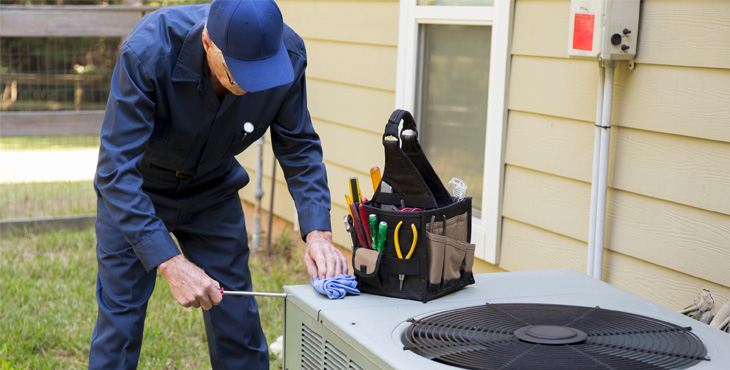 HVAC technician doing AC maintenance on an outdoor unit